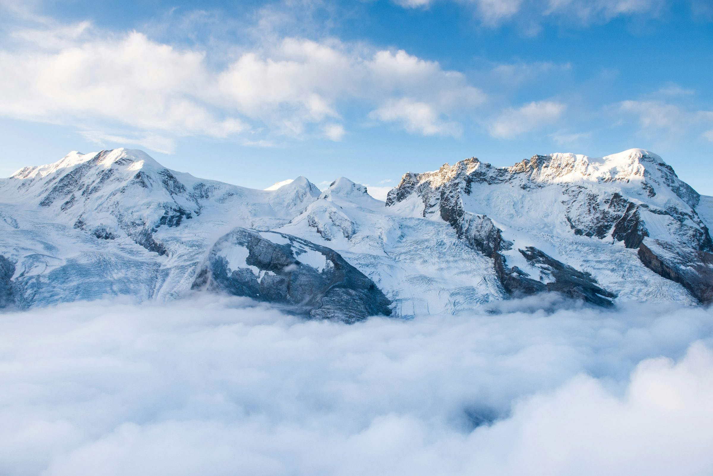 Snow-covered alpine peaks rising above a sea of cloud